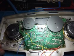 Wnętrze urządzenia elektronicznego z płytką drukowaną i kolorowymi przewodami.