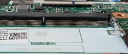 Zbliżenie na slot RAM SO-DIMM na płycie głównej laptopa z widocznymi pinami i zatrzaskiem