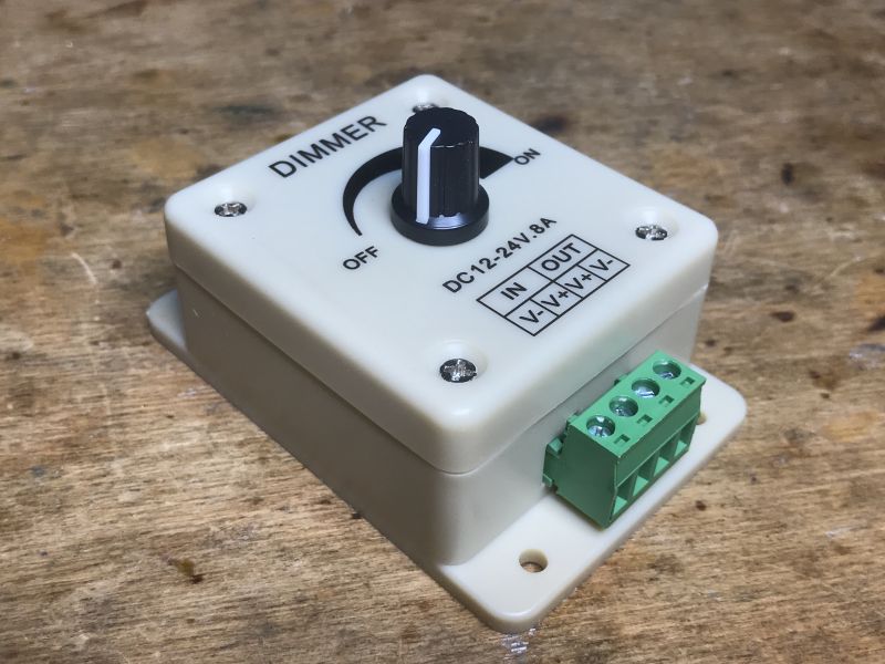 Manual LED dimmer in a plastic enclosure with a knob and screw terminals, placed on a workbench.