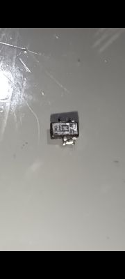 Zdjęcie małego, czarnego elementu elektronicznego z białym nadrukiem „RL” na jasnym tle.
