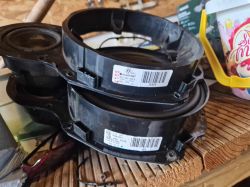 Dwa głośniki samochodowe w obudowach leżące na drewnianej powierzchni.