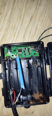 Wnętrze plastikowej obudowy z widoczną płytką drukowaną i kablami.