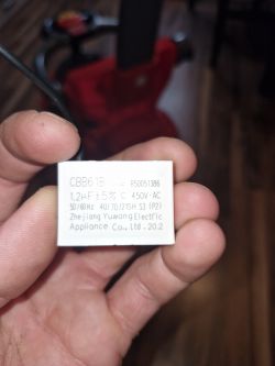 Capacitor labeled CBB61B, with specifications 1.2uF ±5% C 450V AC, held in hand.