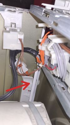 Widok wnętrza pralki Bosch z przewodami elektrycznymi i złączkami.