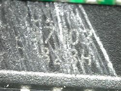 Zbliżenie na fragment układu scalonego z trudnymi do odczytania oznaczeniami.