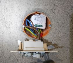 OXT Wi-Fi relay installed in a flush-mounted wall box with visible wiring and a detached light switch.