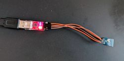USB-RS232 converter with red LED lighting connected via wires to a small circuit board.