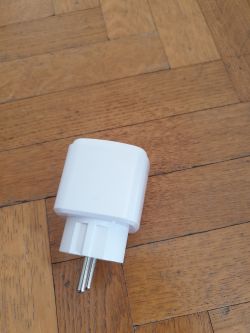 White smart plug on a wooden floor.