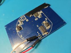 Close-up of a blue printed circuit board with electronic components and connected wires.