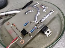 Zbliżenie na ręcznie wykonaną płytkę z triakiem i elementami elektronicznymi.