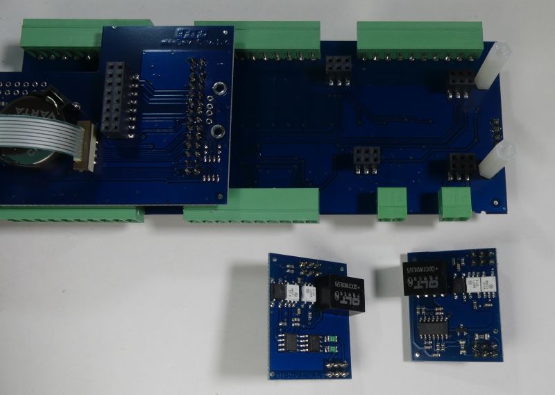 Niebieskie płytki PCB z zielonymi złączami śrubowymi; jedna duża płytka i dwie mniejsze z przekaźnikami