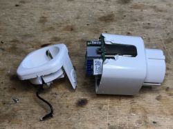 Disassembled power socket with WiFi module and antenna on a wooden surface.