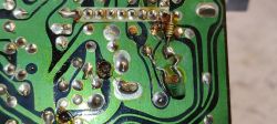 Płytka PCB z dolutowanym kondensatorem i rezystorem po stronie ścieżek.