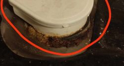 Plastikowy element z widoczną rdzą lub zabrudzeniem wokół uszczelki, otoczony czerwonym okręgiem.