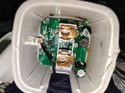 View of the inside of a disassembled electrical socket with a visible circuit board and electronic components.