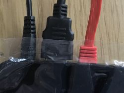 Zbliżenie na trzy podłączone kable: HDMI, USB i czerwony kabel SATA, na tle drewnianej powierzchni.
