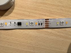 Section of LED strip with visible pins and electronic components.