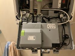 Wnętrze otwartego urządzenia elektronicznego z widocznymi przewodami i panelami w obudowie.