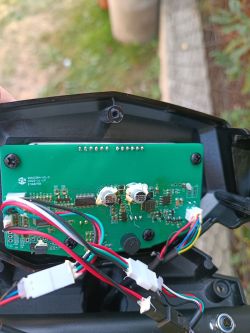 Wnętrze obudowy elektrycznej hulajnogi z widocznym obwodem elektronicznym i przewodami.