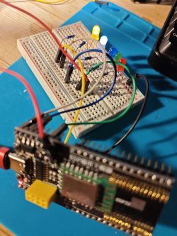 Close-up of a breadboard prototype with five functioning LEDs in different colors connected to a microcontroller.