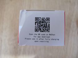 QR Code and Instructions on Packaging A QR code and instructions in English on a white box against a wooden background.