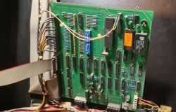 Zielona płytka PCB z układami scalonymi, przekaźnikiem i taśmą przewodów w obudowie