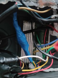 Zbliżenie na wnętrze obudowy z przewodami, złączami i sterownikiem elektrycznym owiniętym niebieską taśmą izolacyjną.
