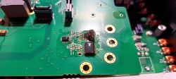 Uszkodzony układ scalony na zielonym PCB z widocznymi śladami przypalenia