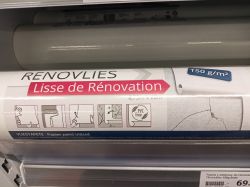 Rolka gładkiej tapety renowacyjnej na półce sklepowej z oznaczeniem Renovlies i informacją o wadze 150 g/m².