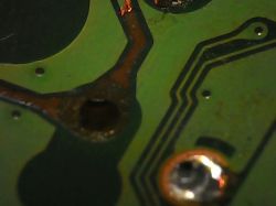 Zbliżenie na płytkę drukowaną z widocznymi ścieżkami i miejscem lutowania.