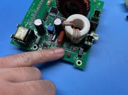 Palec wskazujący na uszkodzonym układzie scalonym na płytce elektronicznej.