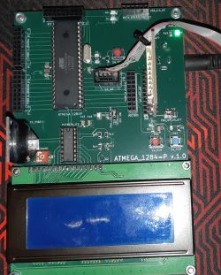 Zbliżenie na płytkę drukowaną z zamontowanymi elementami elektronicznymi, w tym mikrokontroler ATmega1284P i wyświetlacz LCD.