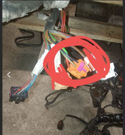 Wiązka kolorowych kabli elektrycznych z zaznaczonym czerwonym kółkiem fragmentem z pomarańczowymi złączkami.