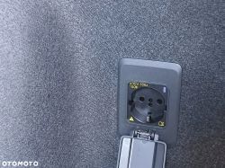 230V power outlet with an open flap mounted on gray felt upholstery