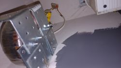 Widok na elektryczną rozdzielnię z licznikiem energii i złączem, część ściany pomalowana na szaro.