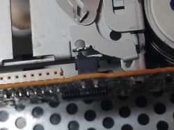 Zbliżenie na mechanizm magnetofonu z widocznym switchem kasety w pozycji otwartej.