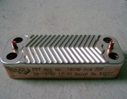 Heat exchanger lying on a surface with metallic grooves and markings.