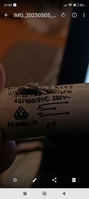 Uszkodzony kondensator KSPpz-10-2 X1Y2 250V z widocznym wybuchem na obudowie trzymany w ręce.