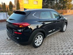 Black Hyundai Tucson SUV parked on a paved driveway, rear three-quarter view.
