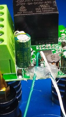 Close-up of a circuit board with attached multicolored wires and electronic components, secured with glue.
