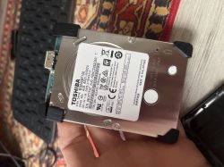 Dysk twardy Toshiba z widoczną etykietą modelu i fragmentem elektroniki przy złączu USB.