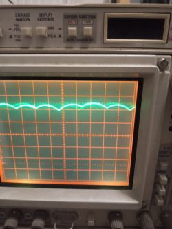 Close-up of an oscilloscope display showing a sinusoidal wave and a measurement grid.