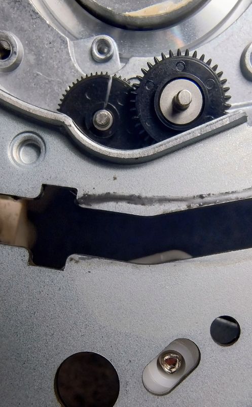 Zbliżenie na dwa czarne zębatki wewnątrz metalowej obudowy magnetowidu