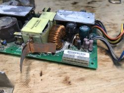 Zbliżenie na uszkodzony zasilacz impulsowy LiteOn z odsłoniętymi elementami elektronicznymi i widocznymi śladami korozji.