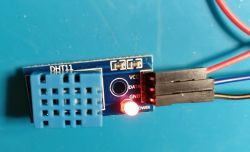 DHT11 module with resistors on a blue background.