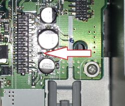Zbliżenie płytki PCB z czerwoną strzałką wskazującą bezpiecznik SMD „M”