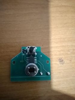 Zdjęcie płytki drukowanej z przyciskiem i elementami elektronicznymi.