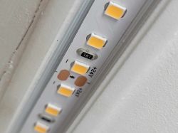 Zbliżenie na fragment taśmy LED 24V zamontowanej w profilu przy ścianie.