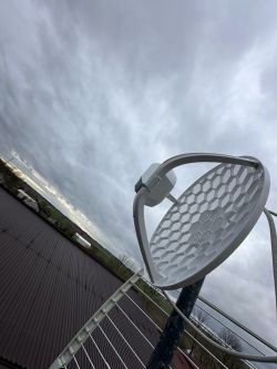 Antena siatkowa zamontowana na dachu, z widokiem na pochmurne niebo.