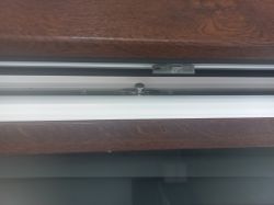 Widok mechanizmu zamykania okna w ramie z tworzywa i drewna
